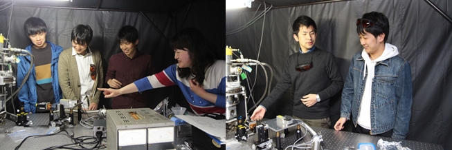 光学実験室で半導体からの発光を測定しながら学生とディスカッションする富永助教